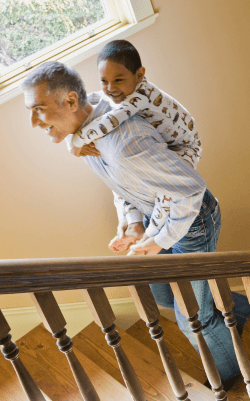 A man running up the stairs with a young child on his shoulders