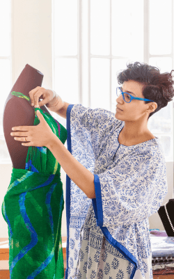 A stylist dressed in a floaty blue and white dress puts the last touches to her latest creation