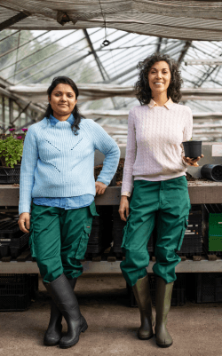 Two female gardeners standing together in greenhouse