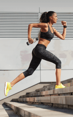 Athletic woman running up stone stairs